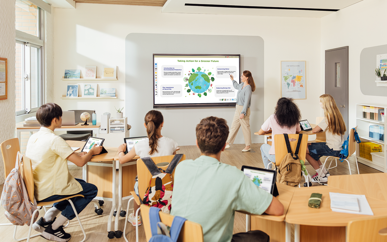 Teacher showing graphic of Earth on interactive display in front of class.