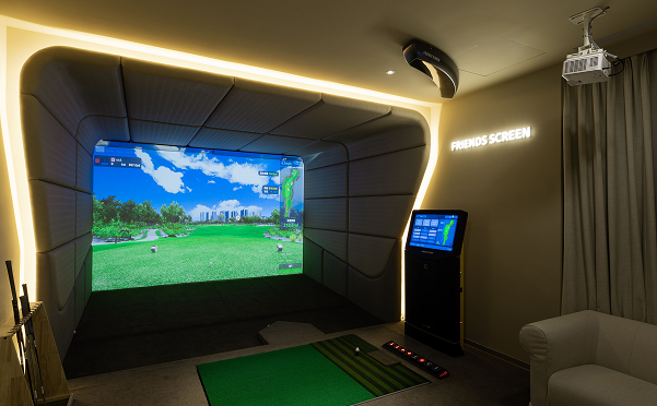 Friends Screen VIP golf simulation room featuring a ceiling-mounted ViewSonic projector and a large immersive screen displaying a virtual fairway.
