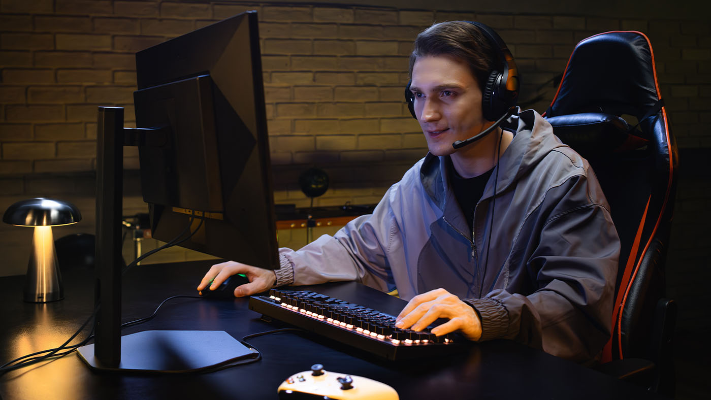 A man with a headset on sitting in front of a gaming monitor.