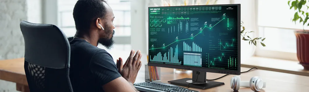 a man sitting at a desk looking at graphs on a monitor
