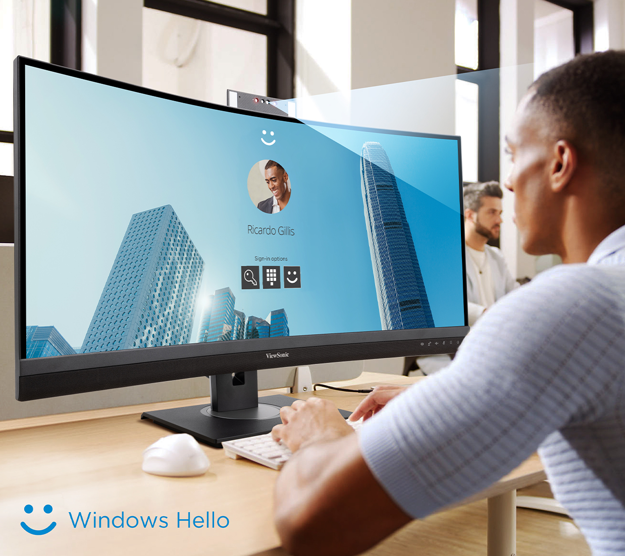 man working at desk, using Windows Hello to log in to his computer