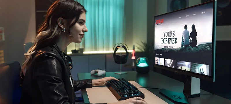 woman sitting at desk using a ViewSonic monitor to watch a show
