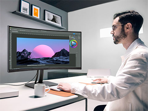 Man working at a desk using a ViewSonic ColorPro monitor for high-accuracy video editing, photography, and graphic design.