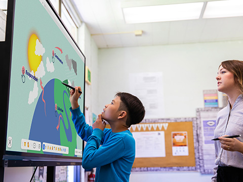 Student using pen on a ViewBoard to work on a science project while his teacher observes.