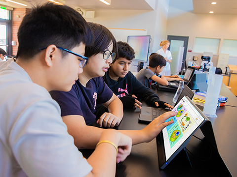 Students gathered around a portable monitor to view a science lesson