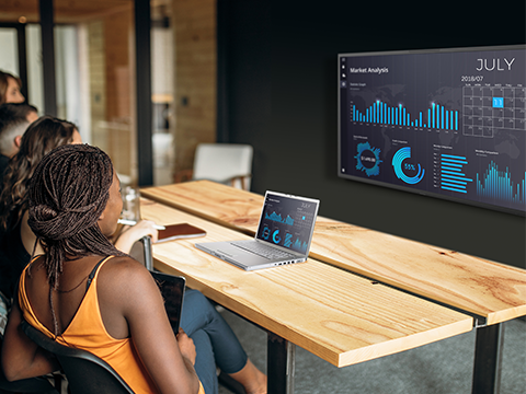 a group of people in a conference room looking at an IFP.  A laptop on the table shows the same image.