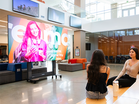 School cafeteria with 3 commercial displays placed on wall above the counter used as digital menus