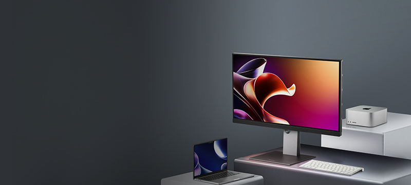 a woman uses graphic design software on two monitors