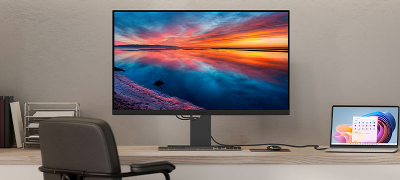 a laptop connected to a large monitor both sitting on a desk