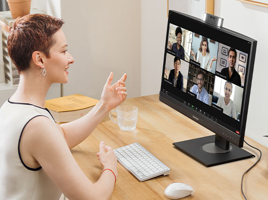 a businesswoman on a video call using a monitor with integrated webcam