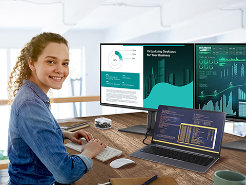 Nurse working on a computer and a monitor with a privacy screen with people nearby