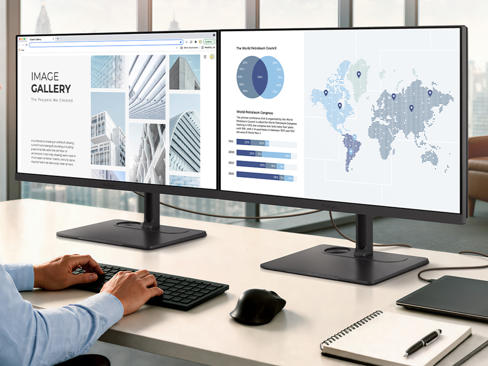 A man sitting at a dual monitor setup.  The monitors are connected via a single cable.