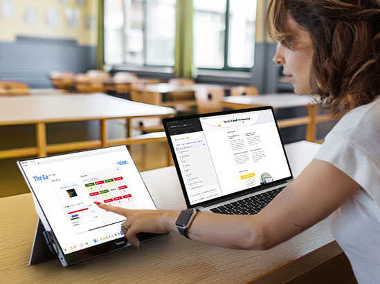 a teacher working on a laptop with a connected second screen.