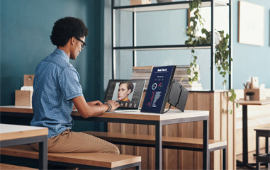 Man working remotely at a desk with laptop and portable monitor