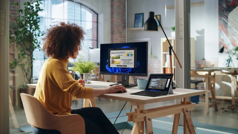 a woman working on a laptop with connected monitor