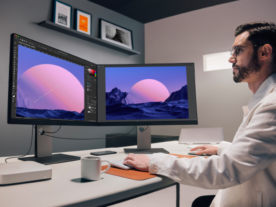 a man sits in front of a dual monitor setup