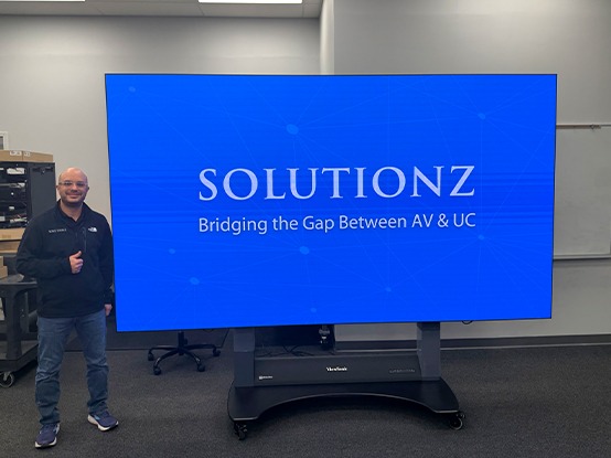 Owner of Solutionz standing in the showroom next to a ViewSonic dvLED