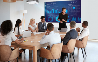 Employees sitting around a conference table looking at infographic projected on the wall