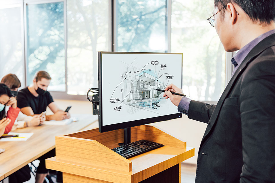 Presenter using a pen display on a podium for interactive presentations.